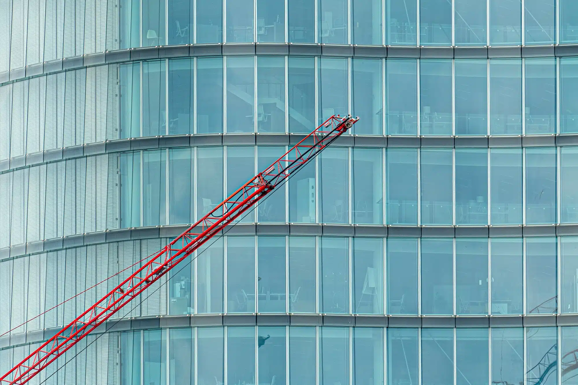 Construction crane in front of a modern building in a glass facade