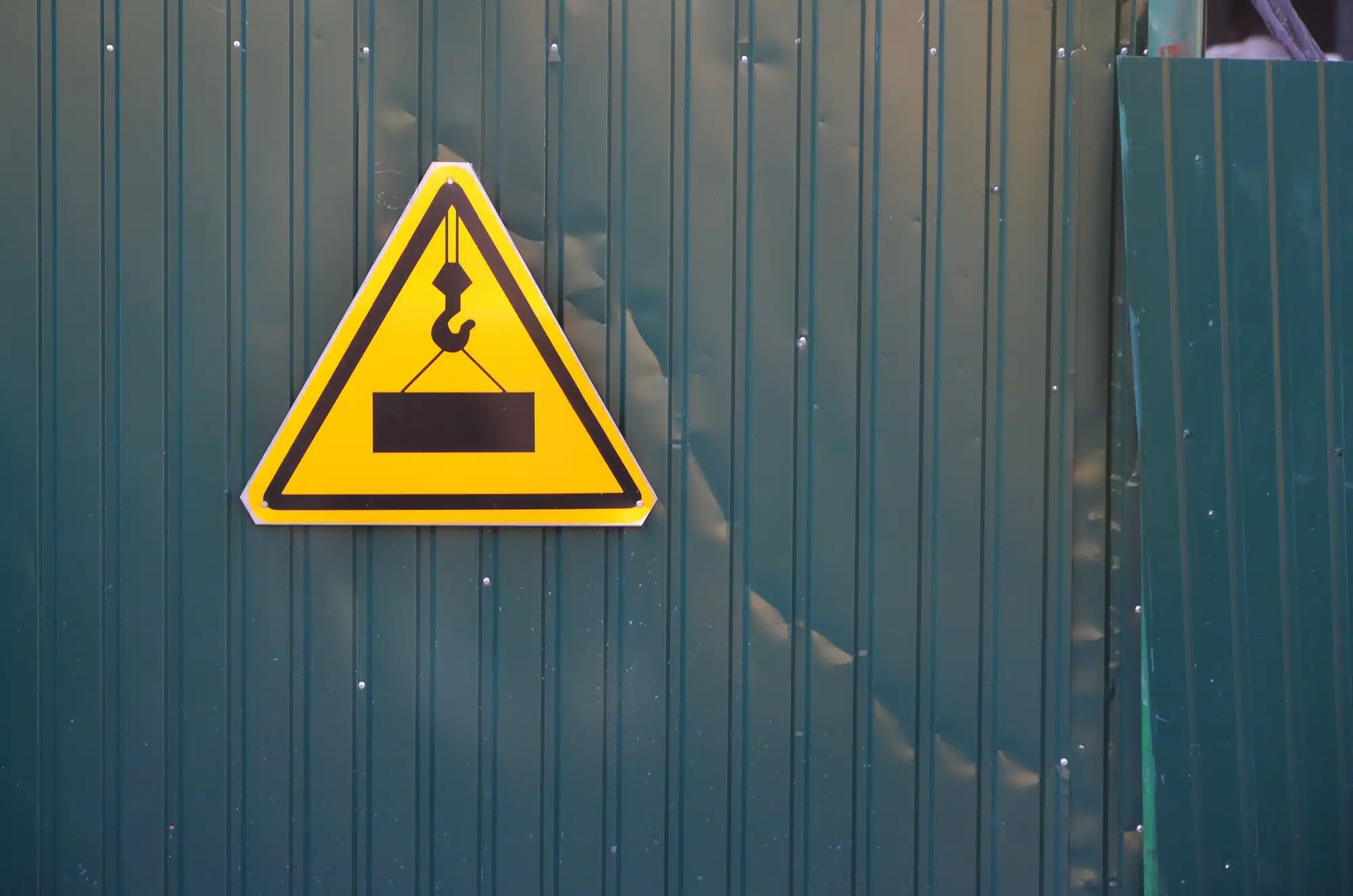 Traffic sign with a picture of a large and heavy square slab hanging from a lifting crane cable
